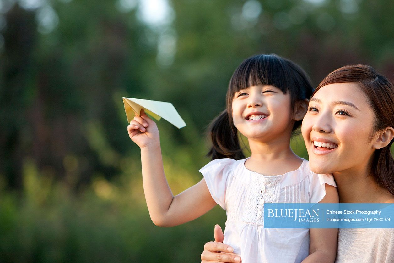 Young Chinese mother and daughter with a paper airplane