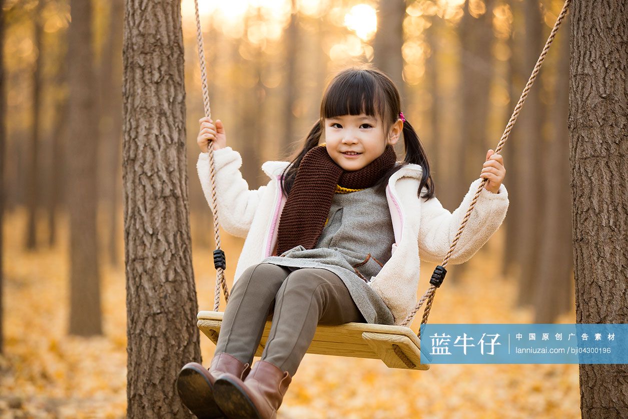 小女孩在秋日树林荡秋千