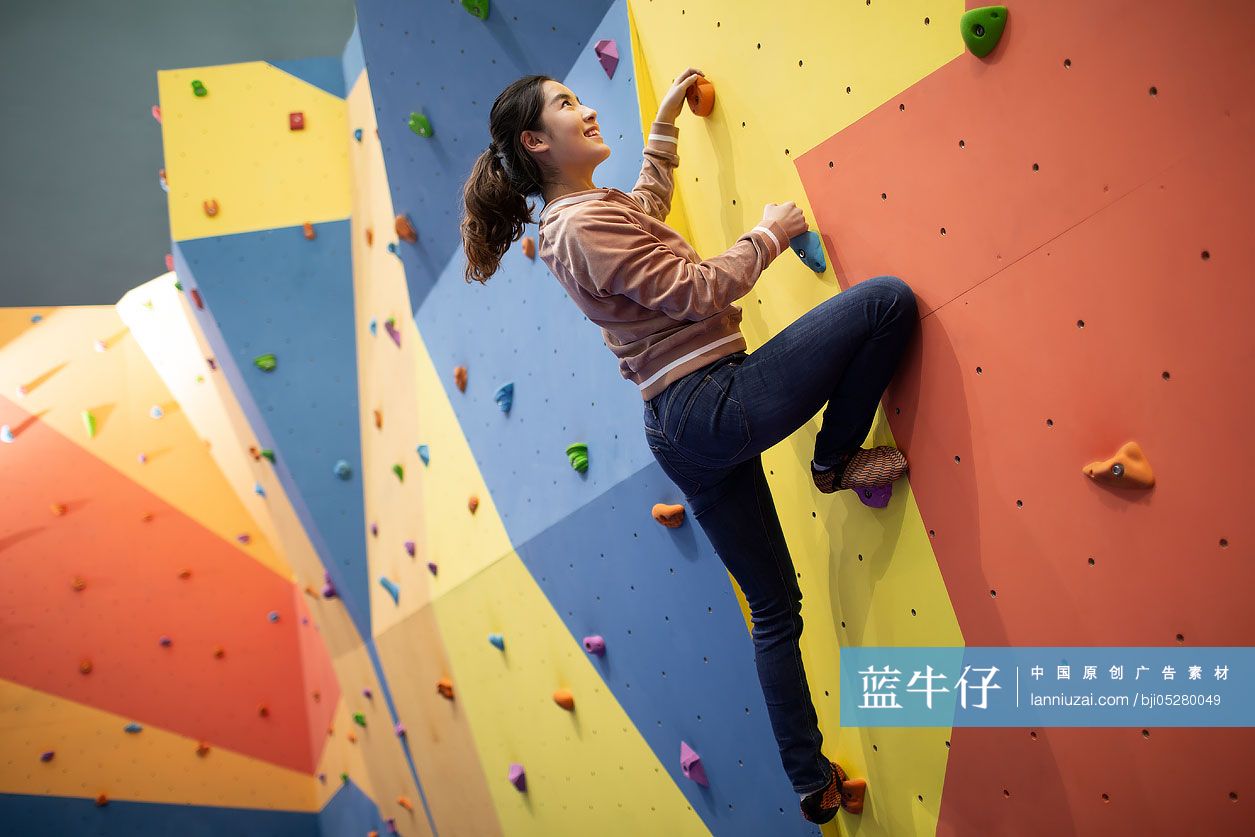 快乐的年轻女孩在健身馆攀岩