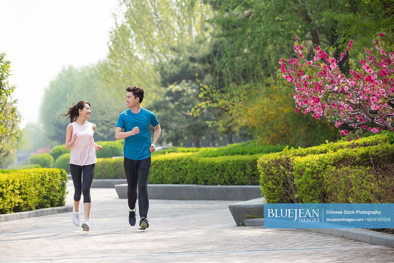 Happy young Chinese couple running in park