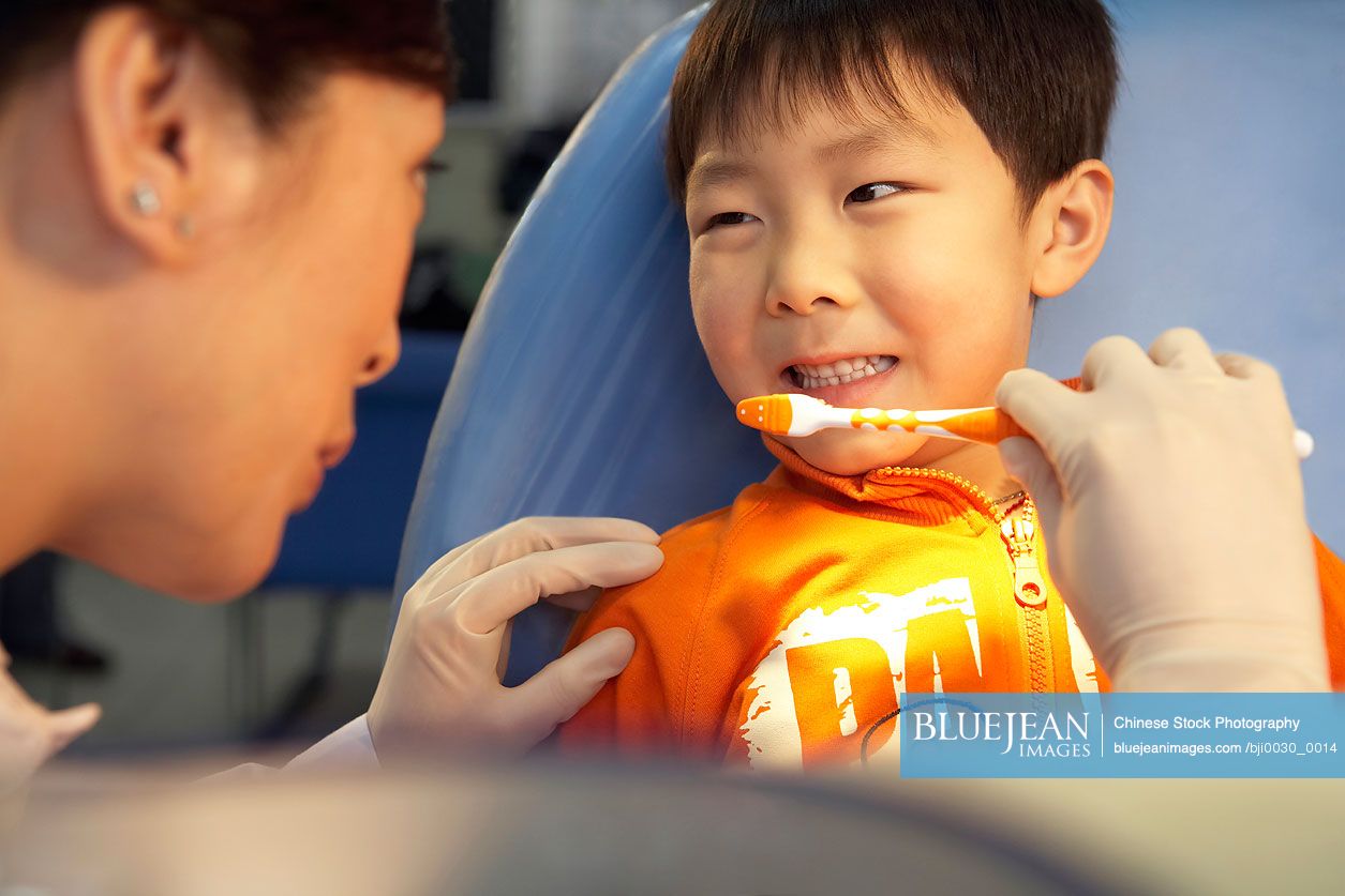 Chinese dentist brushing boy's teeth