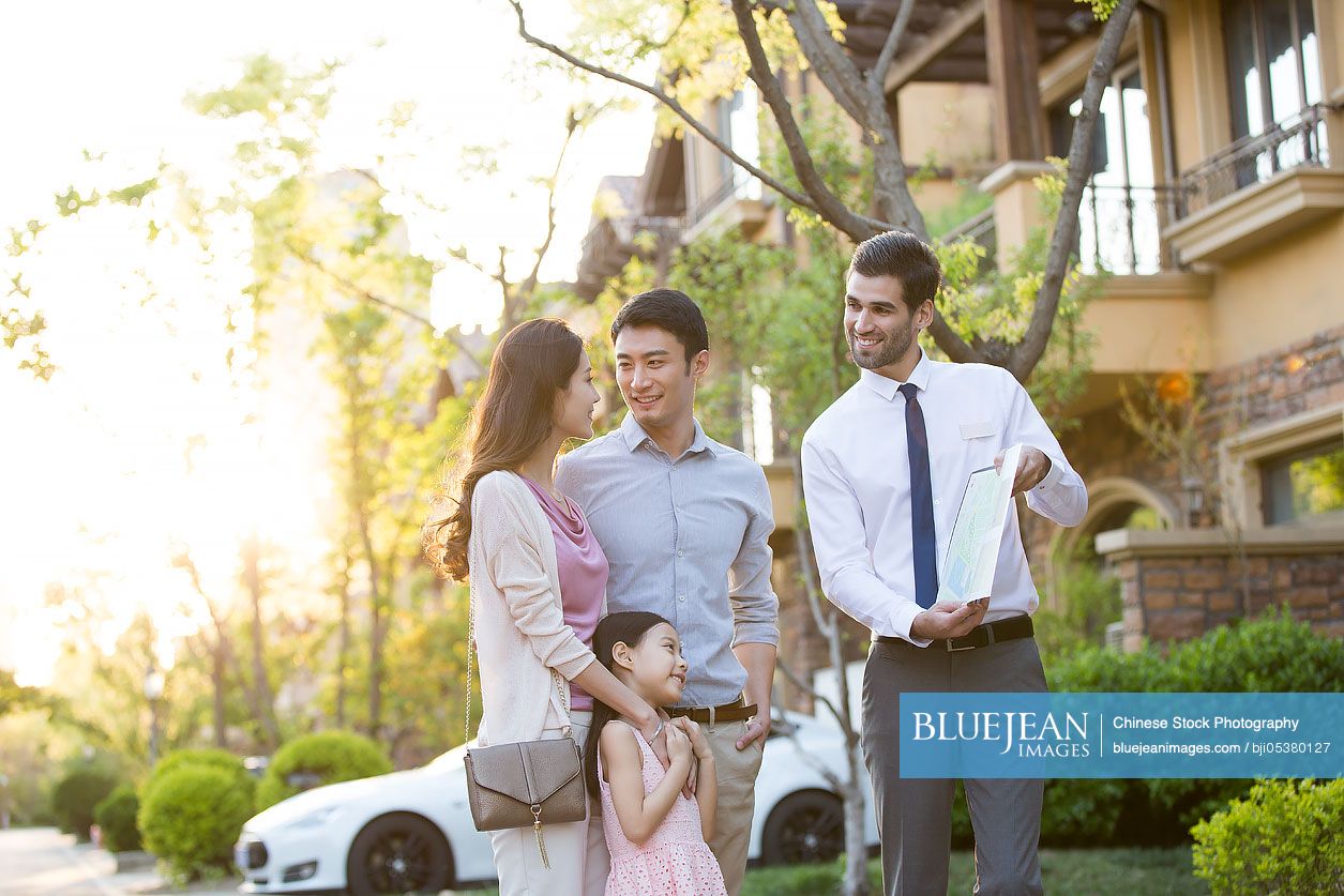 Happy young Chinese family and real estate agent