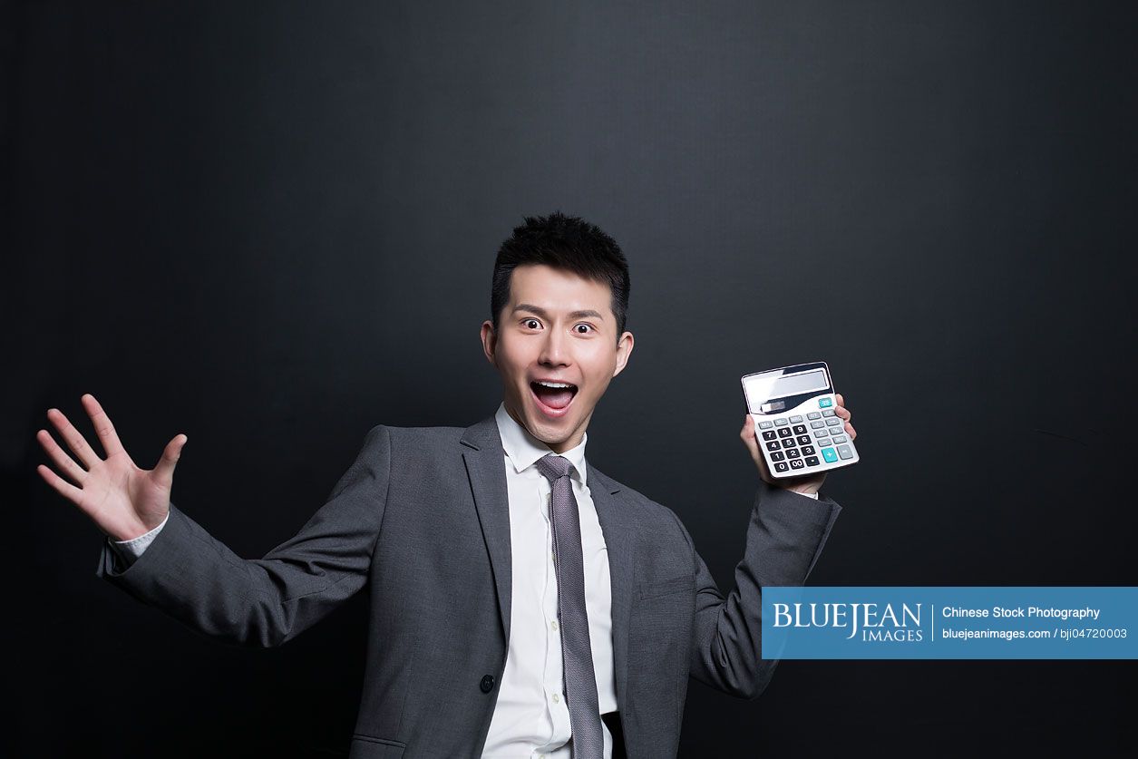 Excited Chinese businessman holding a calculator