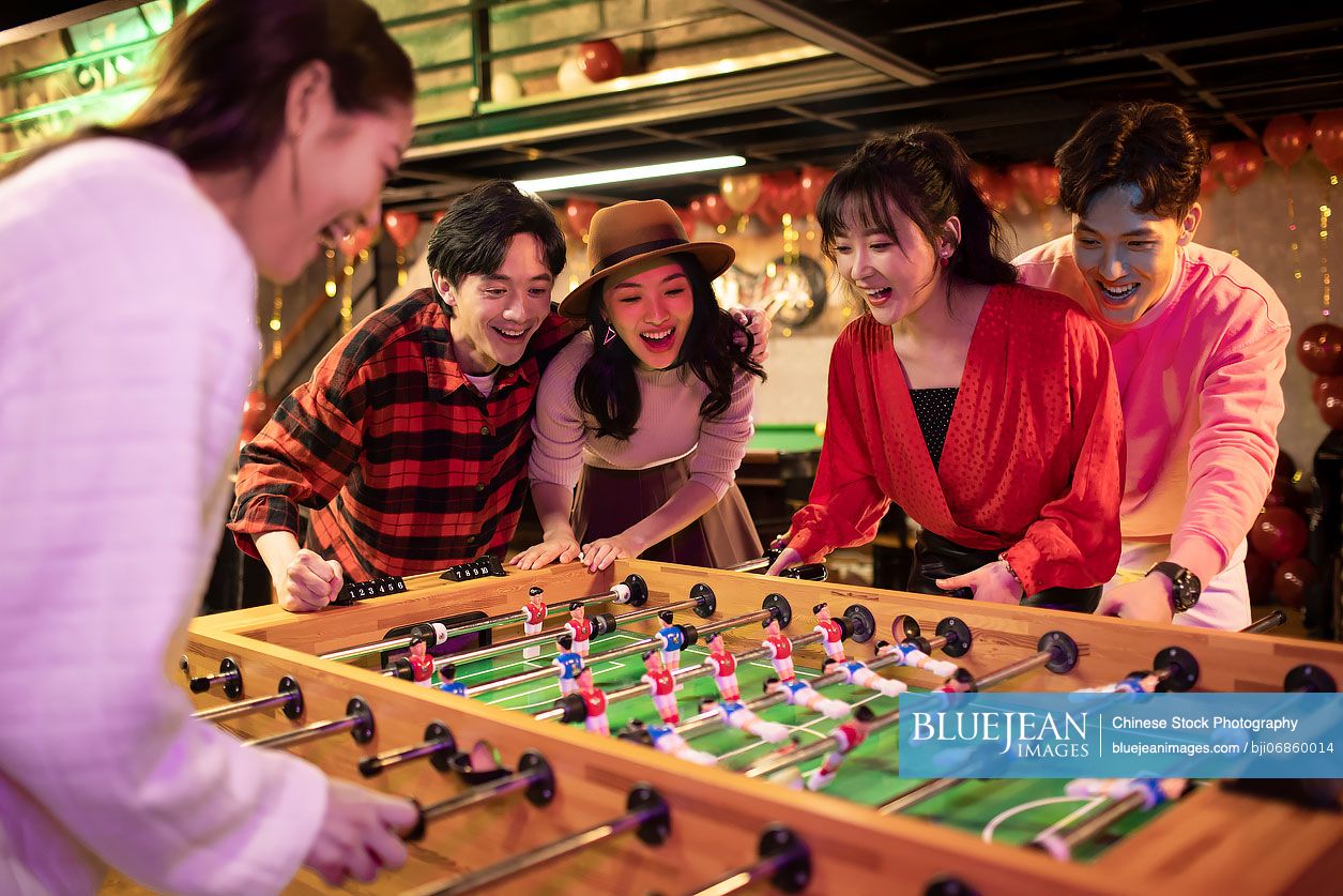 Happy young Chinese friends playing table football