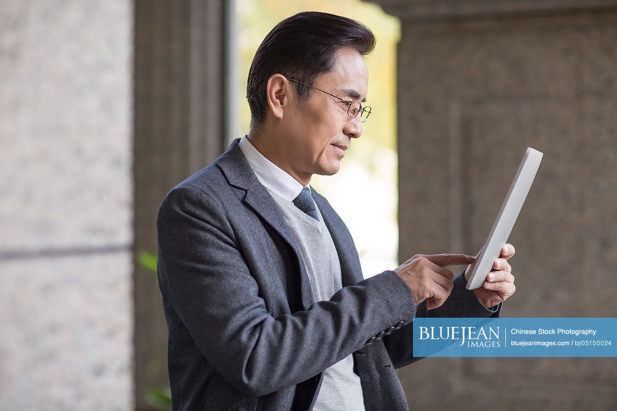 Confident Chinese businessman using digital tablet