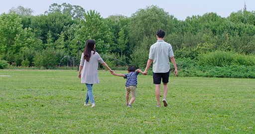 快乐年轻家庭在草地上散步