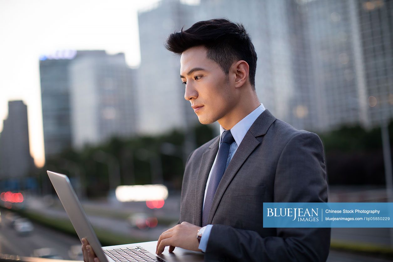 Young Chinese businessman using laptop