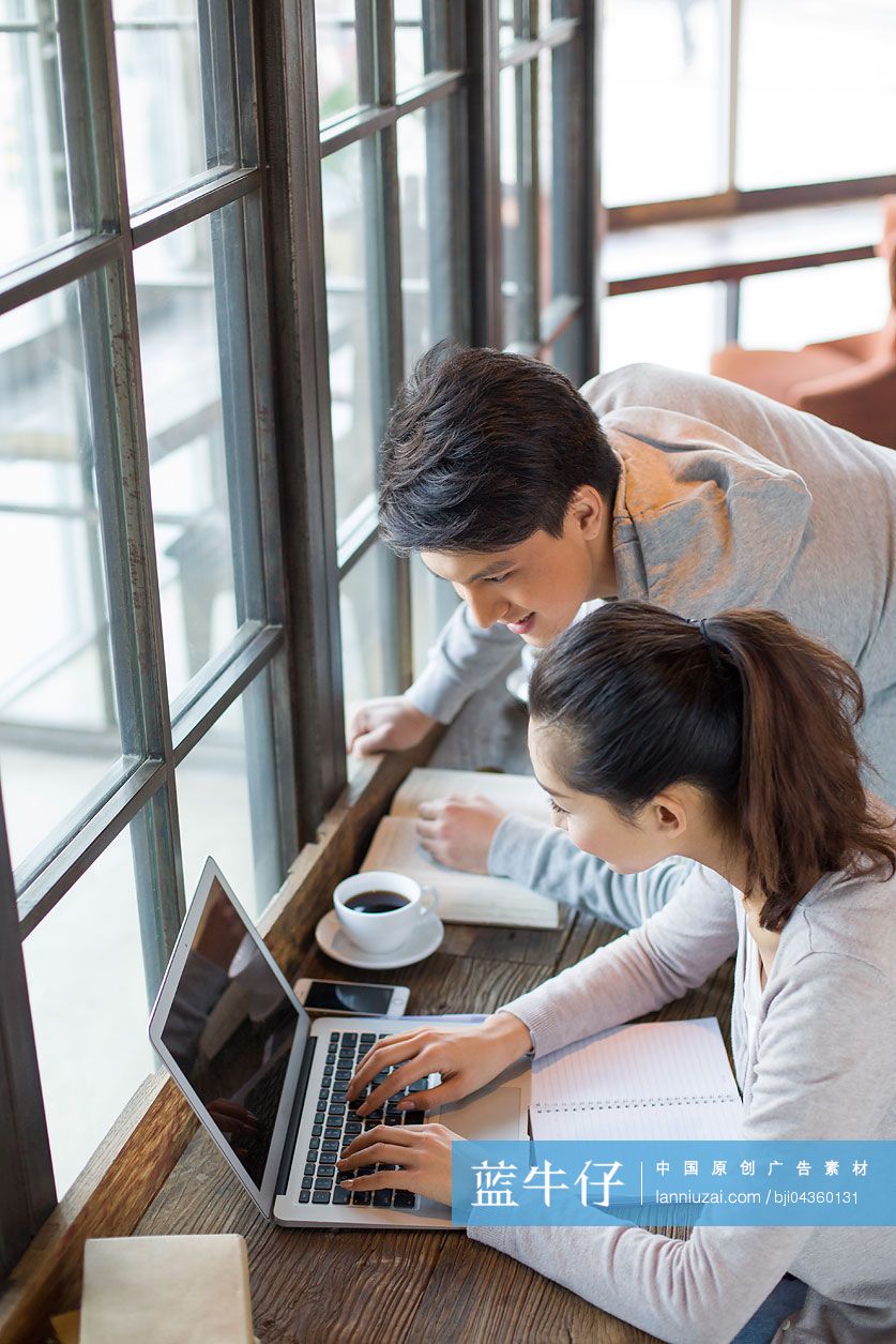 年轻男女在咖啡馆使用笔记本电脑