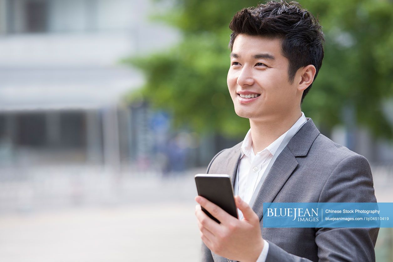 Young Chinese businessman using smart phone