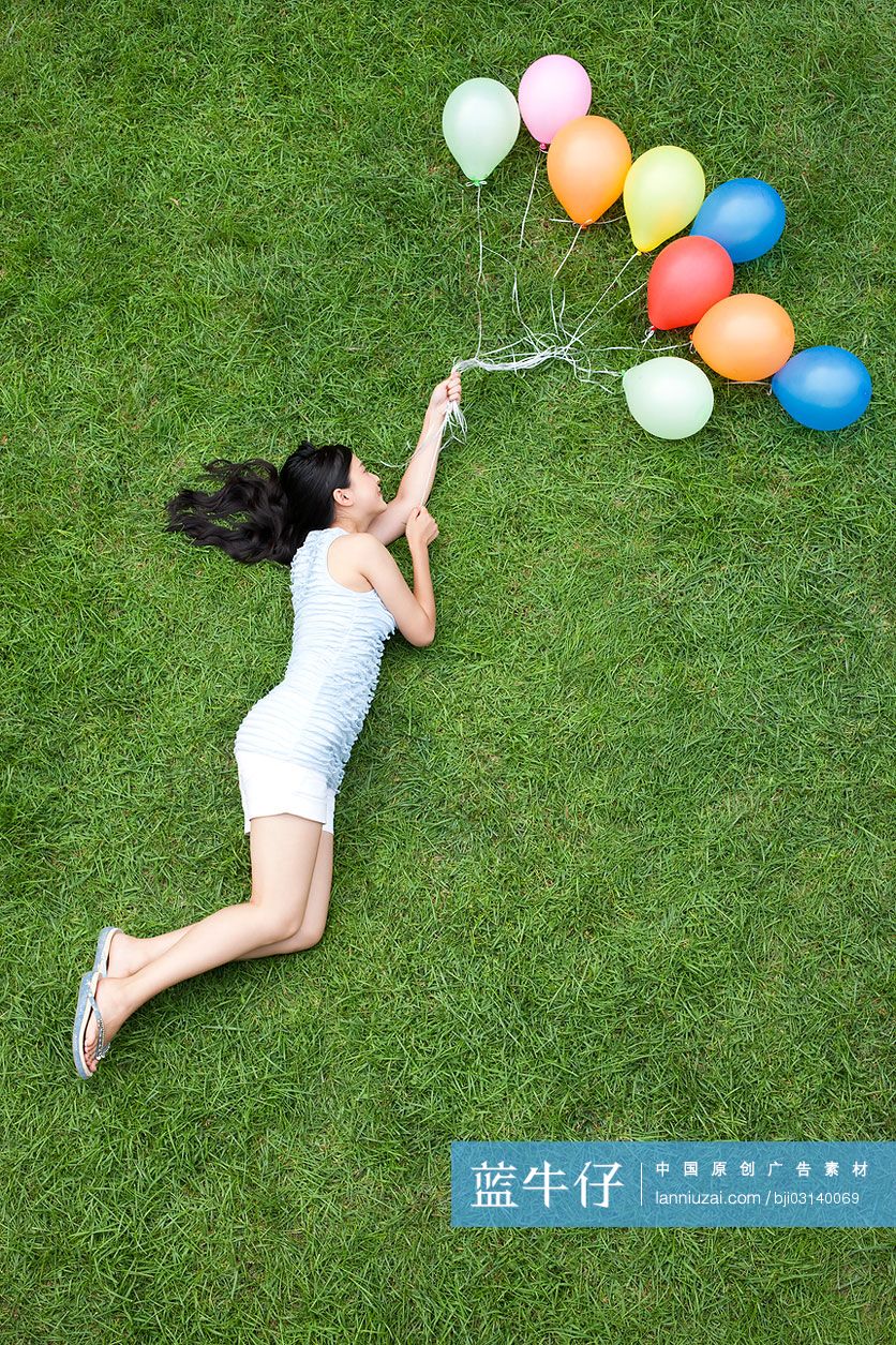 年轻女子在草地上拿着气球