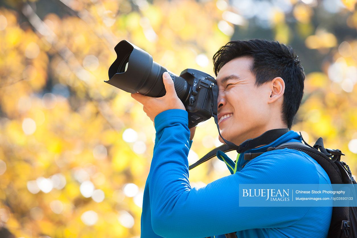 Young male Chinese hiker capturing a picture with SLR camera