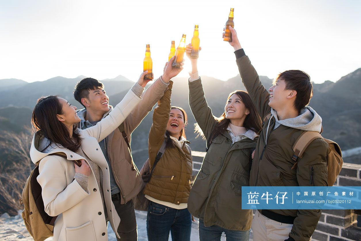 Happy young Chinese friends drinking beer on the Great Wall