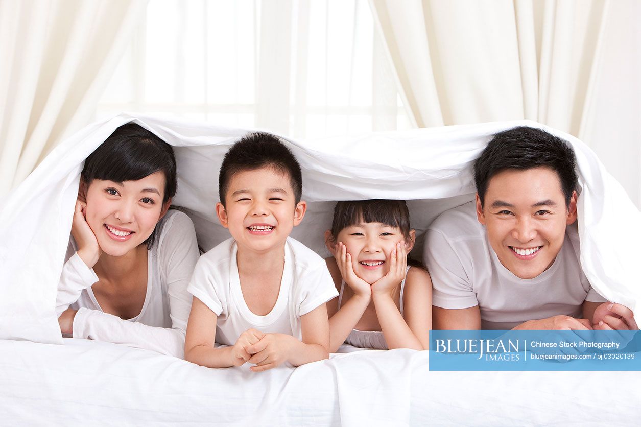 Happy Chinese family lying in bed