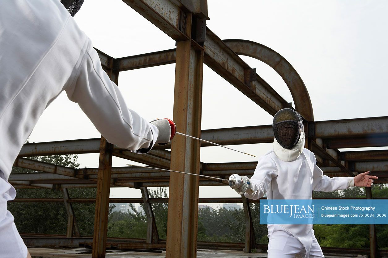 Young Chinese men fencing in a construction site