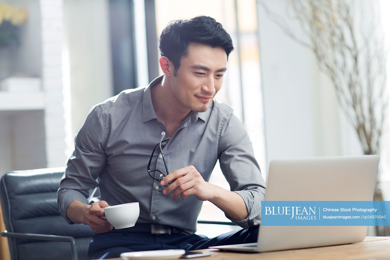 Young Chinese man working with laptop in office