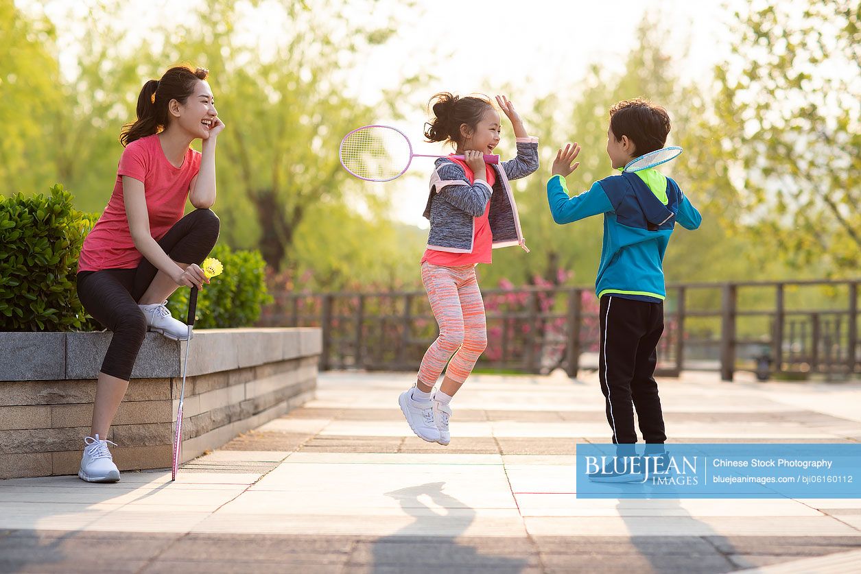 Happy young Chinese family playing badminton in park