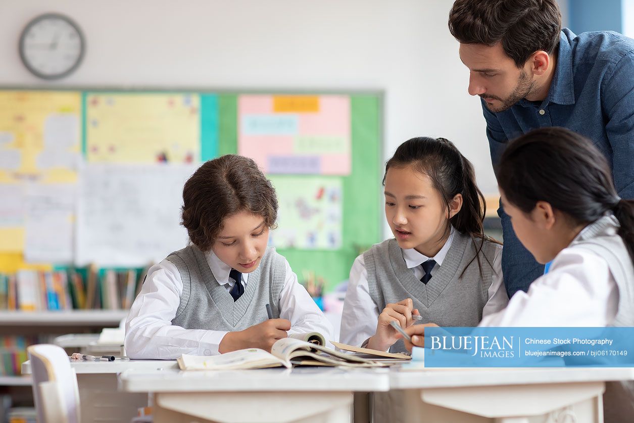 Young teacher helping students in classroom