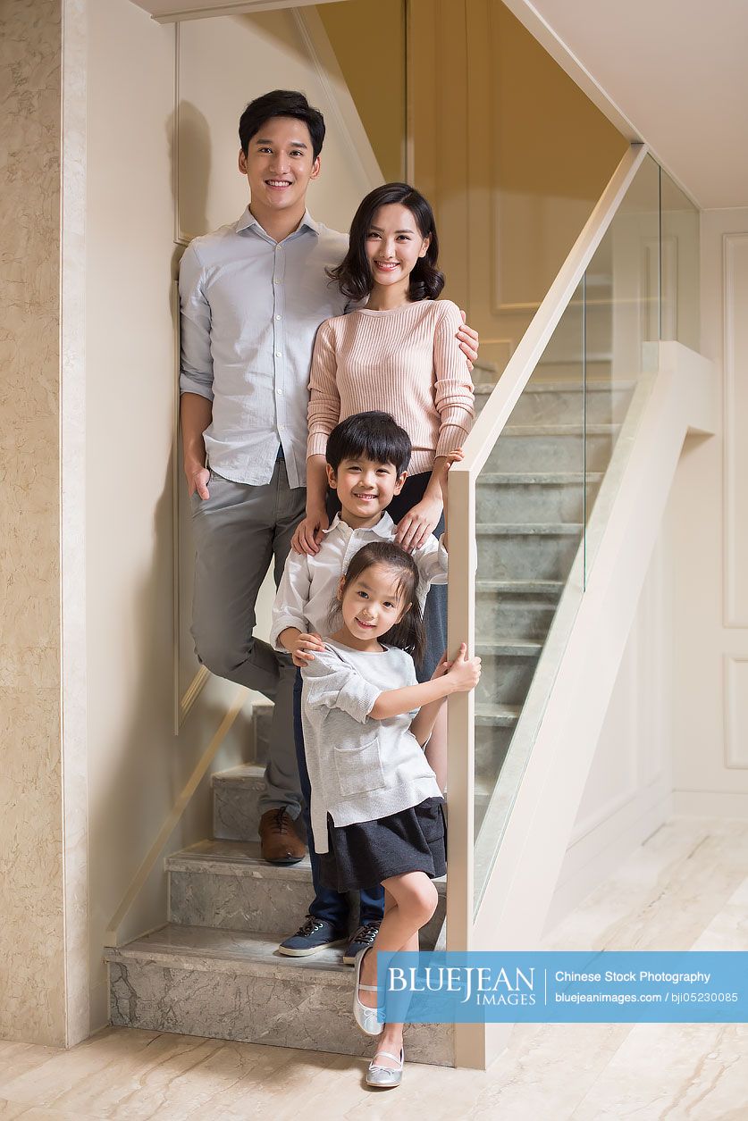 Portrait of cheerful young Chinese family on the stairs