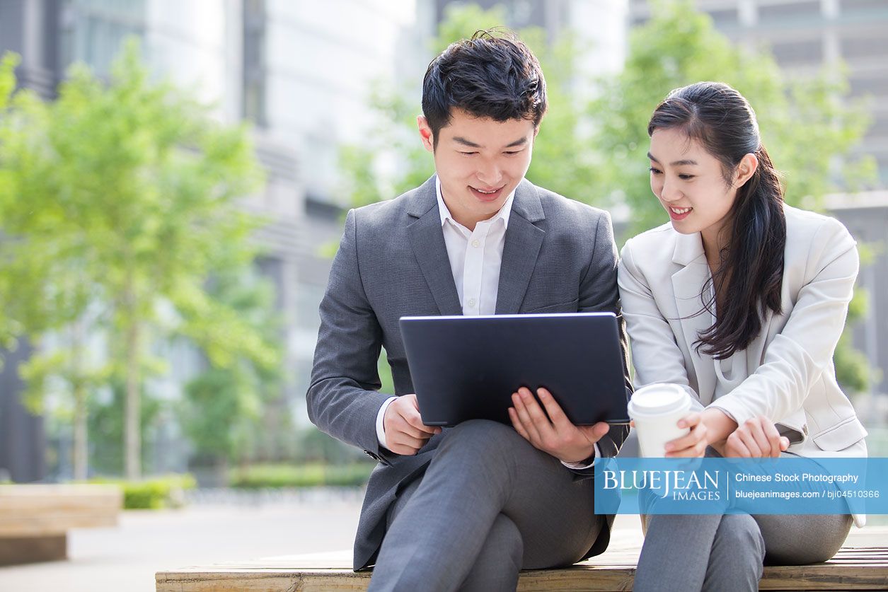 Young Chinese business person working with laptop outdoors