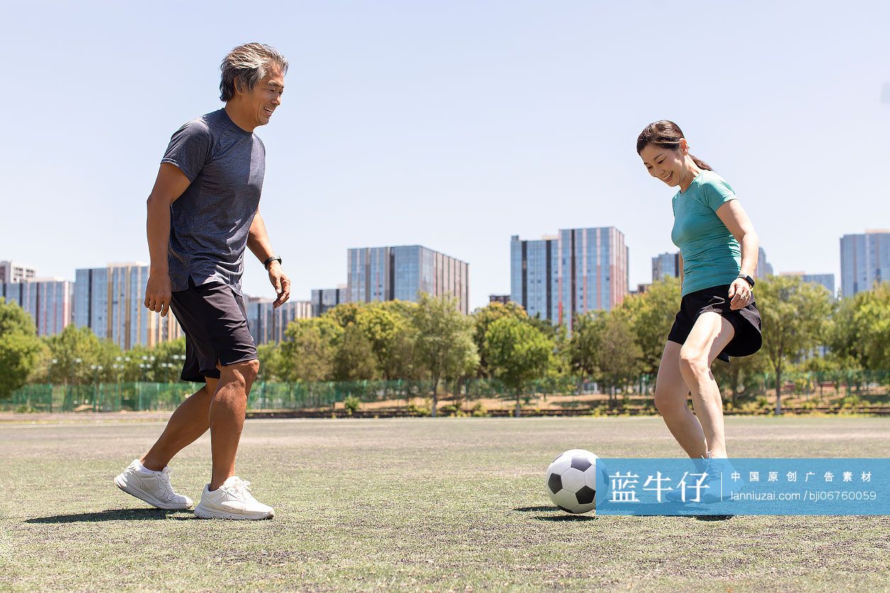开心的中老年夫妇在足球场踢足球