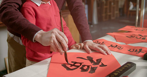 Chinese grandfather and grandson writing calligraphy on couplets,4K