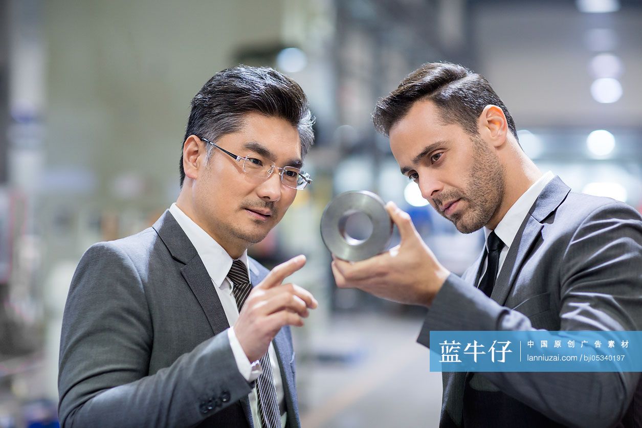 商务人士在工厂检查机械零件