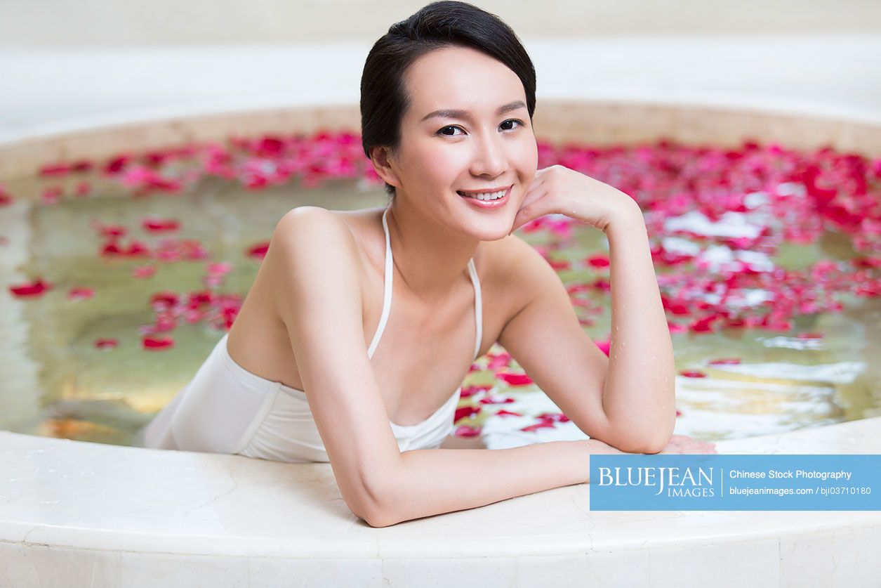 Beautiful young Chinese woman in bathtub with rose petals