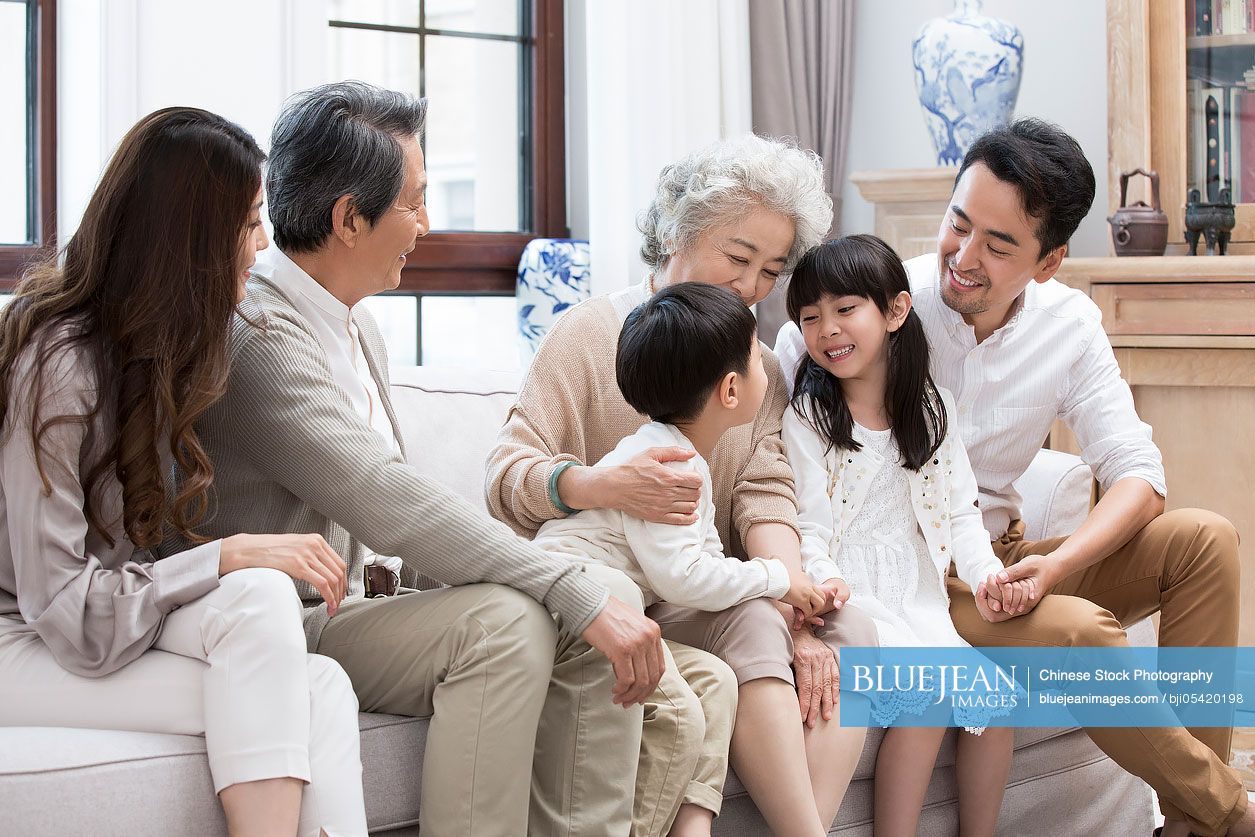Happy Chinese family sitting on sofa