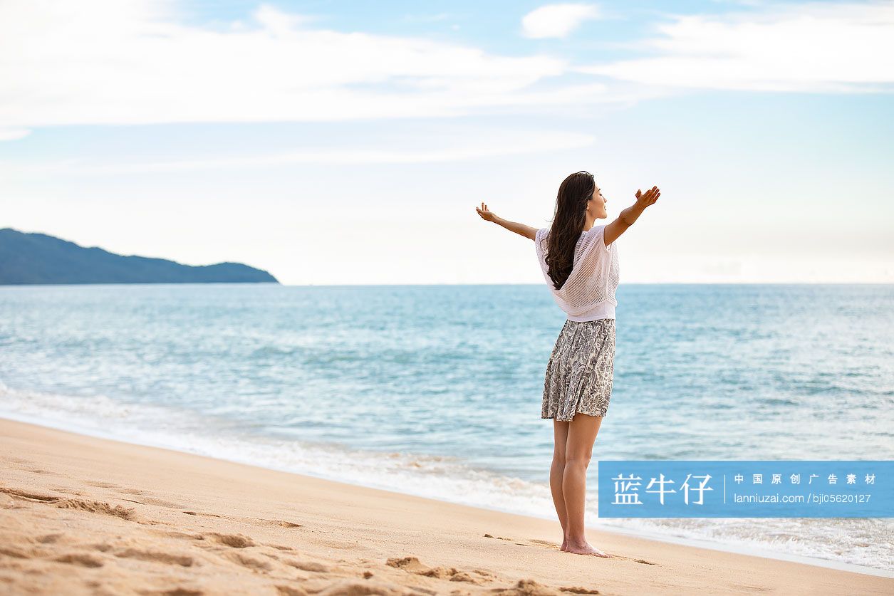 年轻女性在海边张开双臂