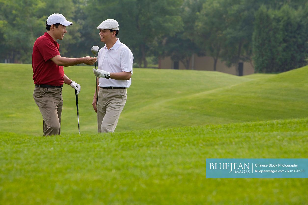 Two Chinese golfers chatting on the course