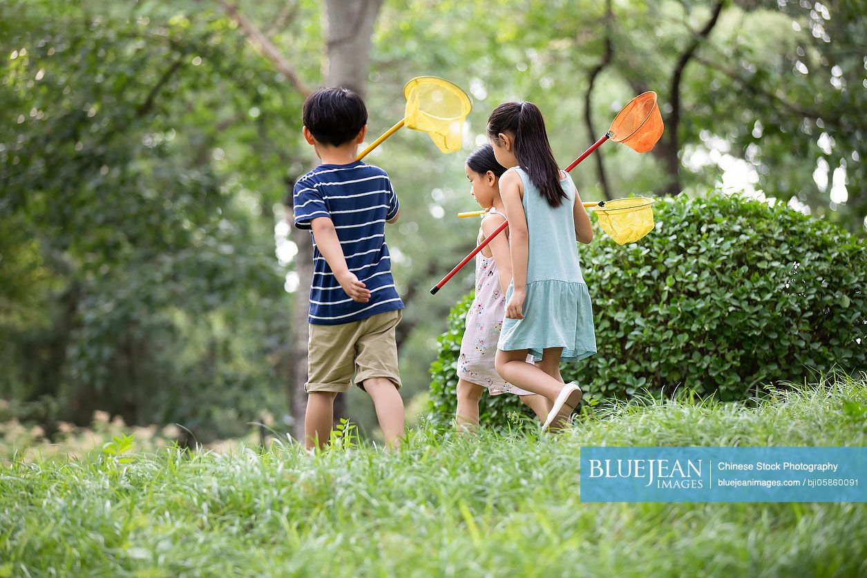 Three Chinese children playing on grass