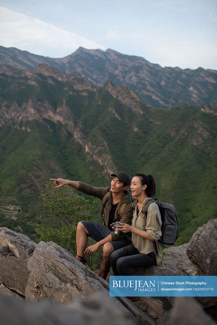 Young Chinese couple taking photos with camera outdoors