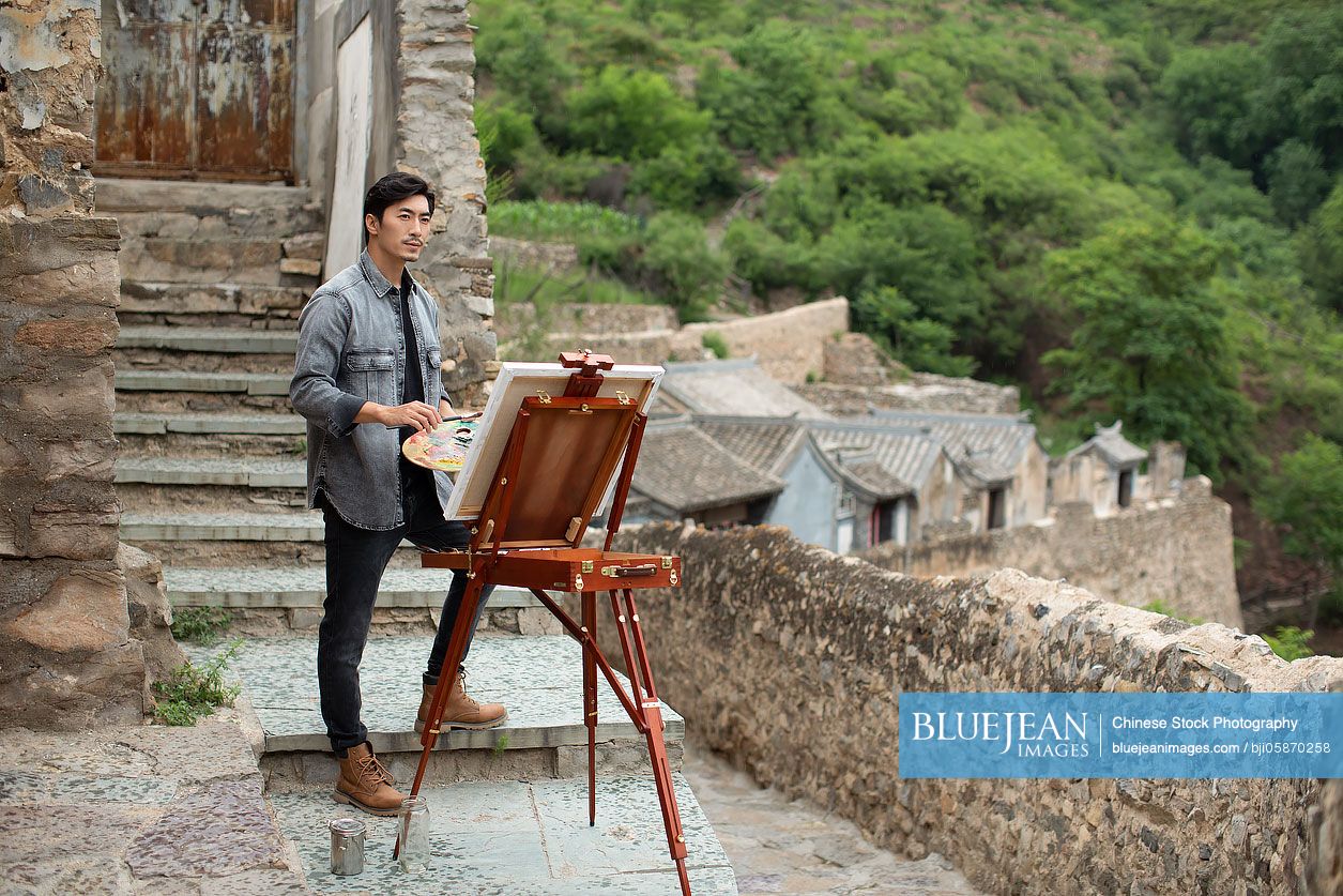 Young Chinese artist painting outdoors