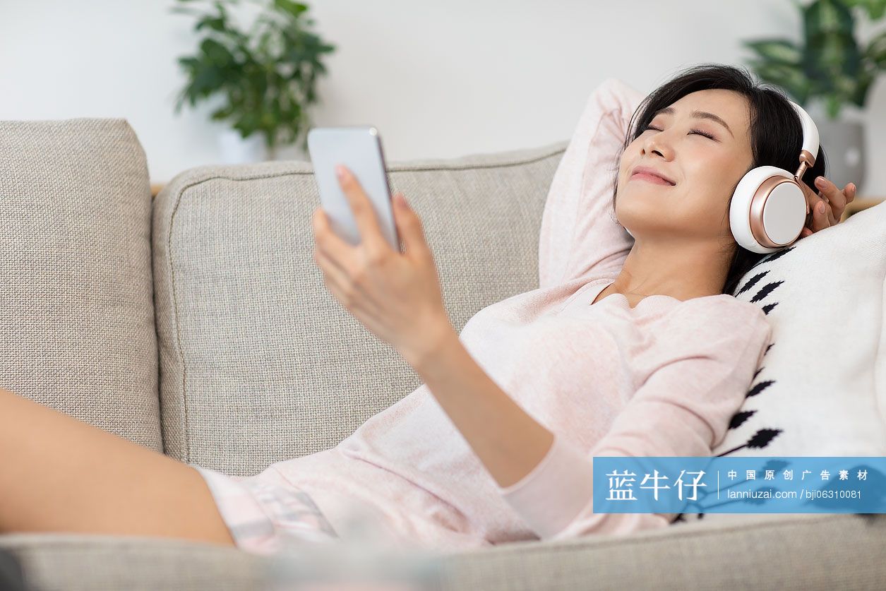 快乐年轻女士在家戴着耳机听音乐