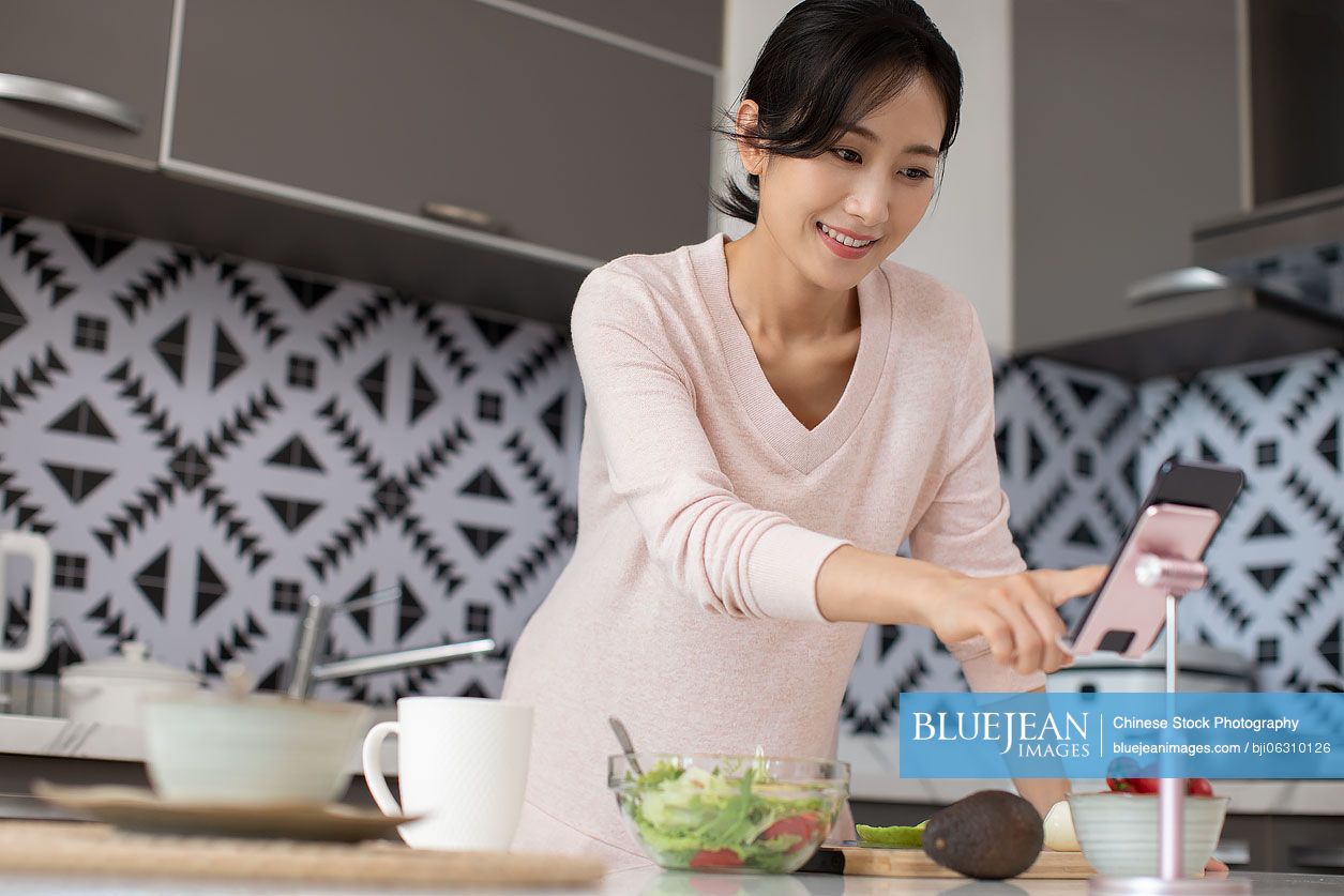 Happy young Chinese woman cooking in kitchen