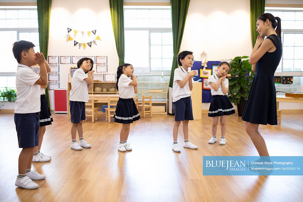 Chinese teacher teaching children dancing in classroom
