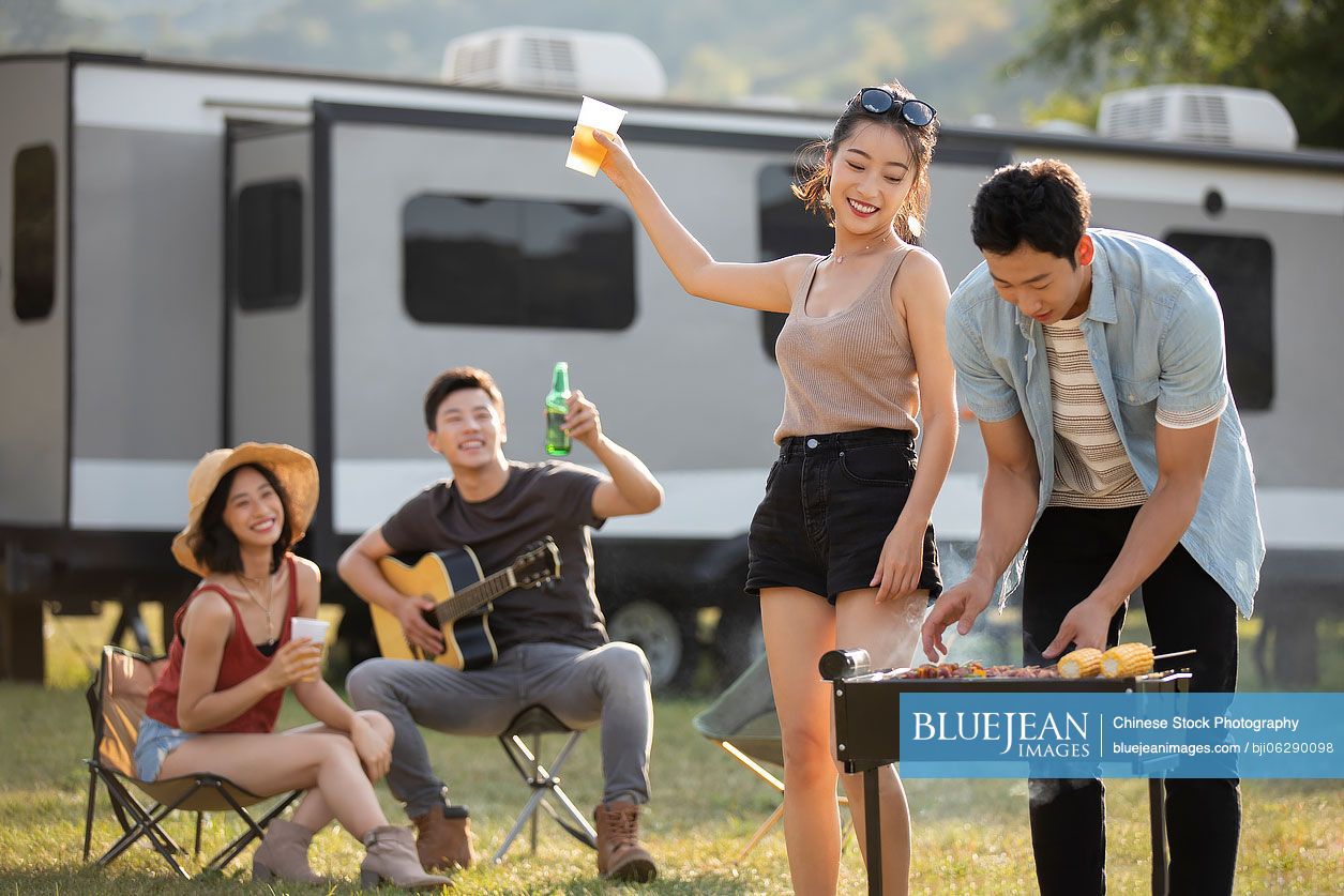 Happy young Chinese friends barbecuing outdoors