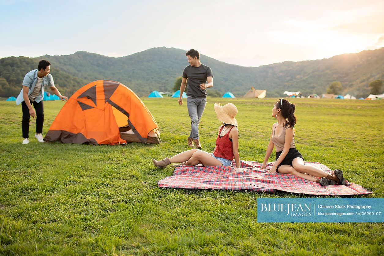 Happy young Chinese friends camping outdoors