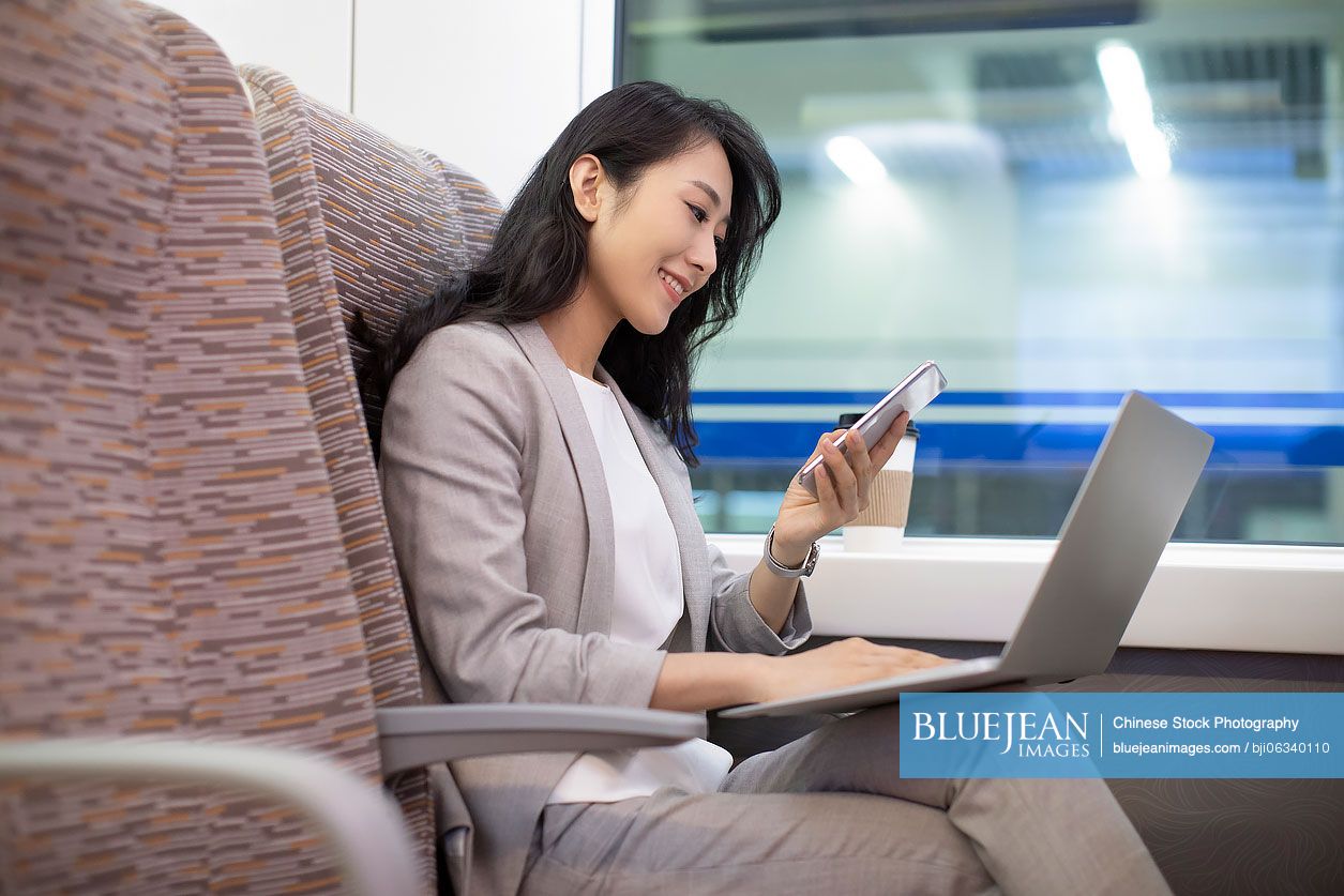 Young Chinese businesswoman using smartphone on high-speed train