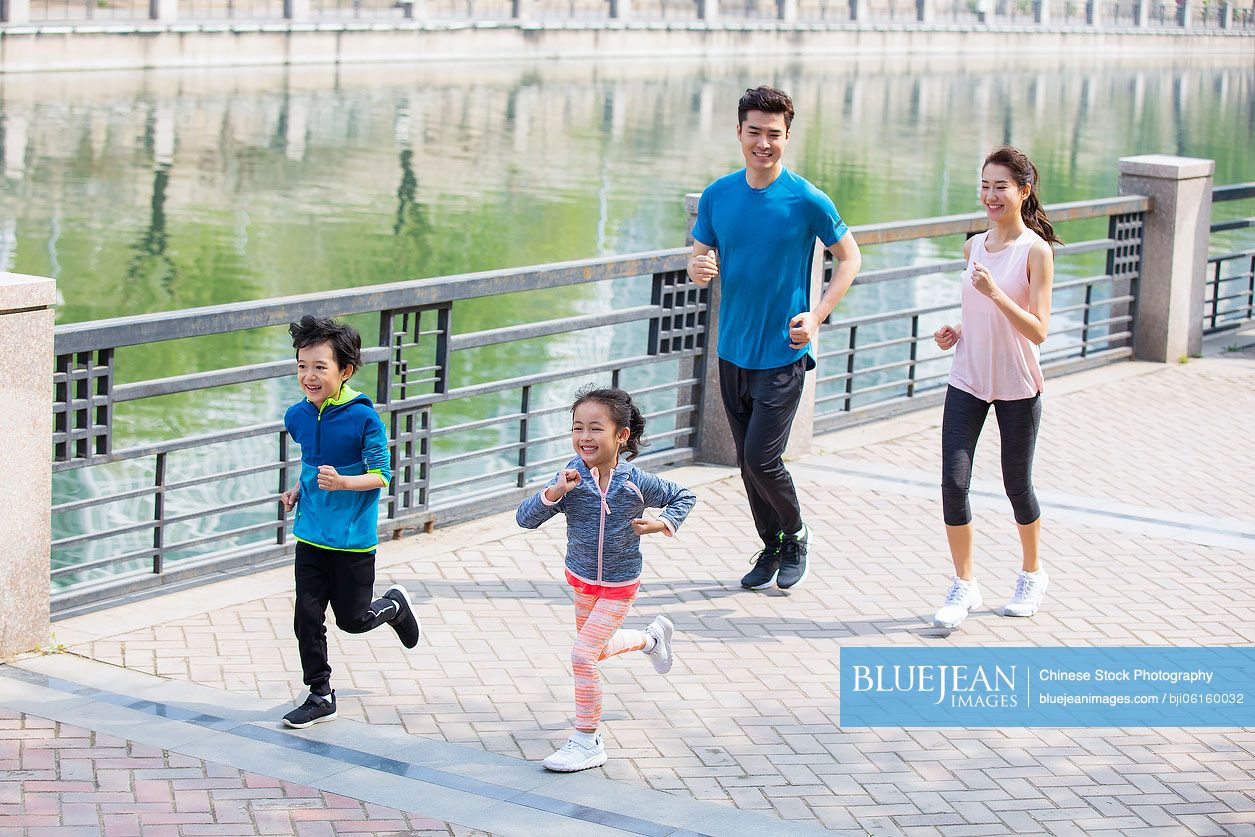 Happy young Chinese family running in park