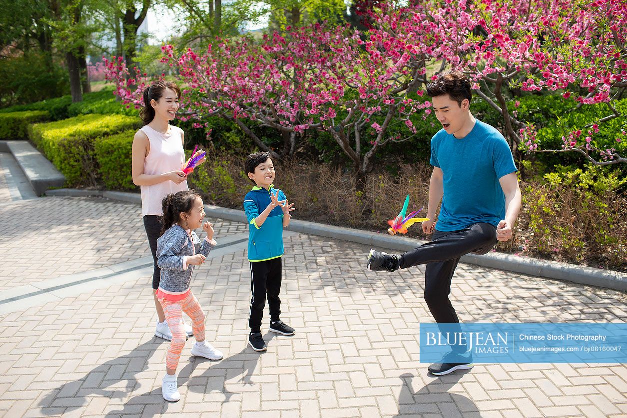 Happy young Chinese family kicking shutterlock in park