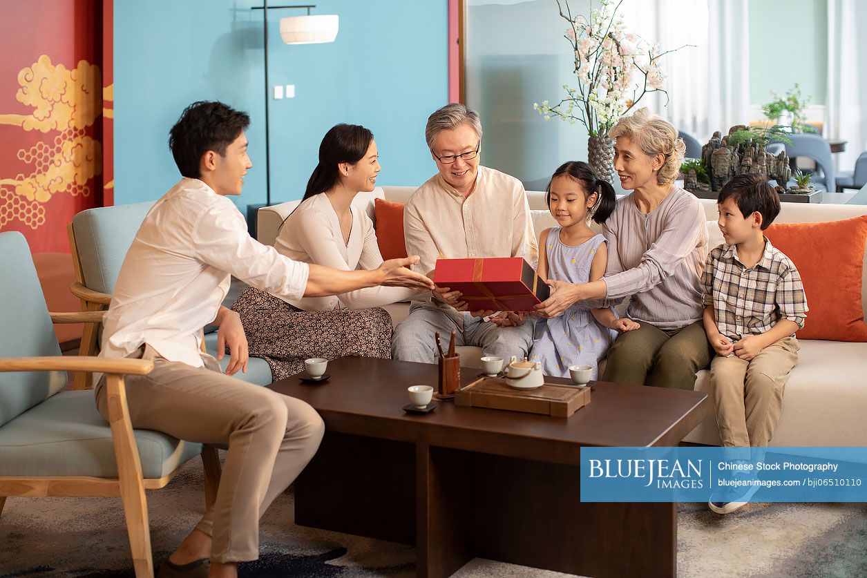 Young Chinese couple giving gift to their parents