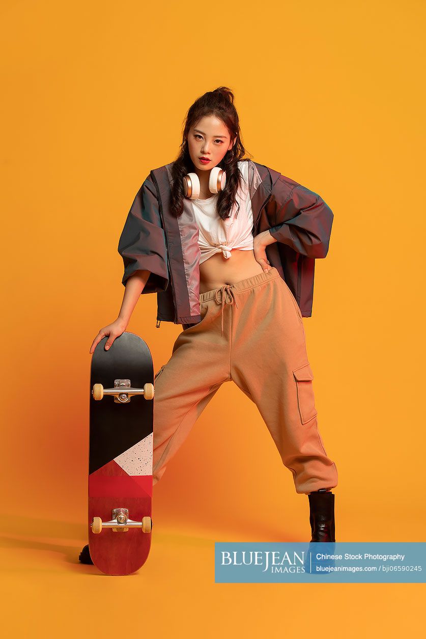 Fashionable young Chinese woman holding a skateboard