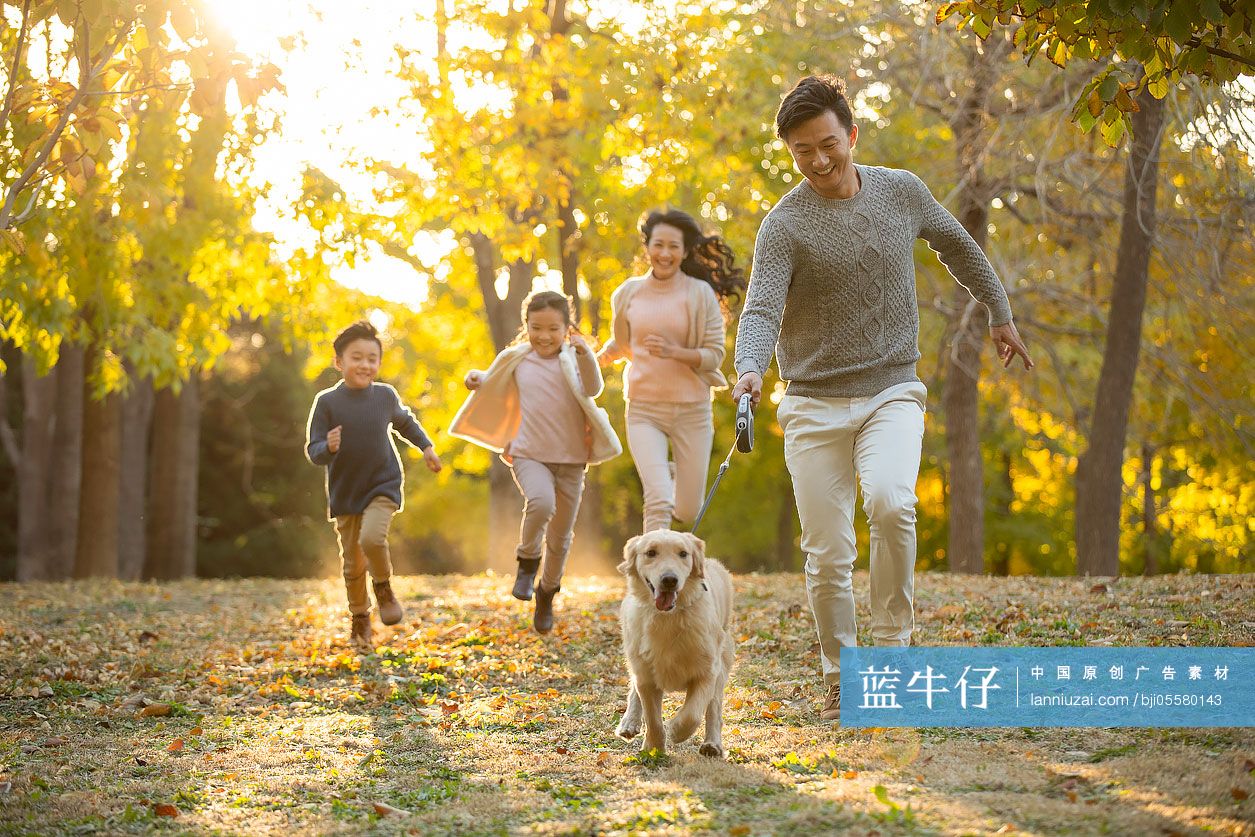 快乐的年轻家庭和狗在秋日的树林里