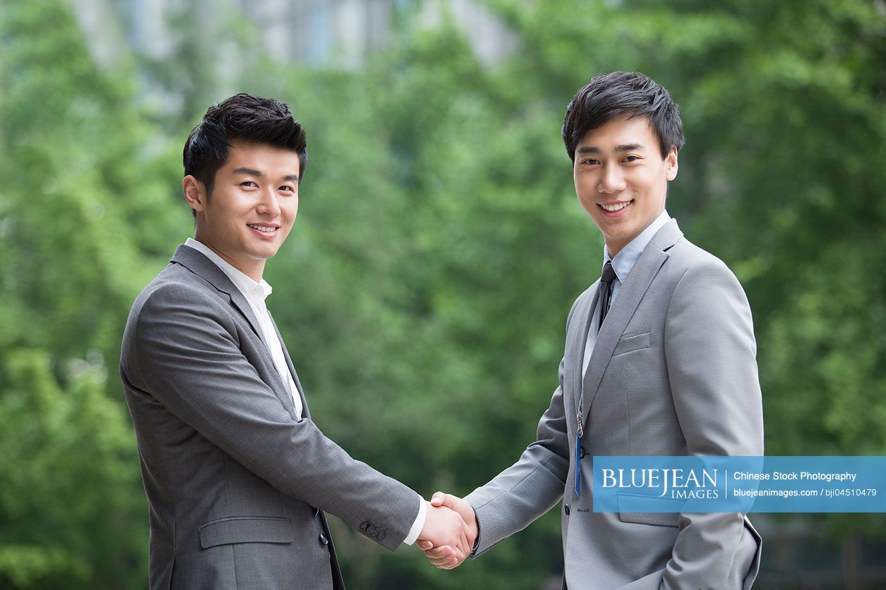 Young Chinese business person shaking hands outdoors