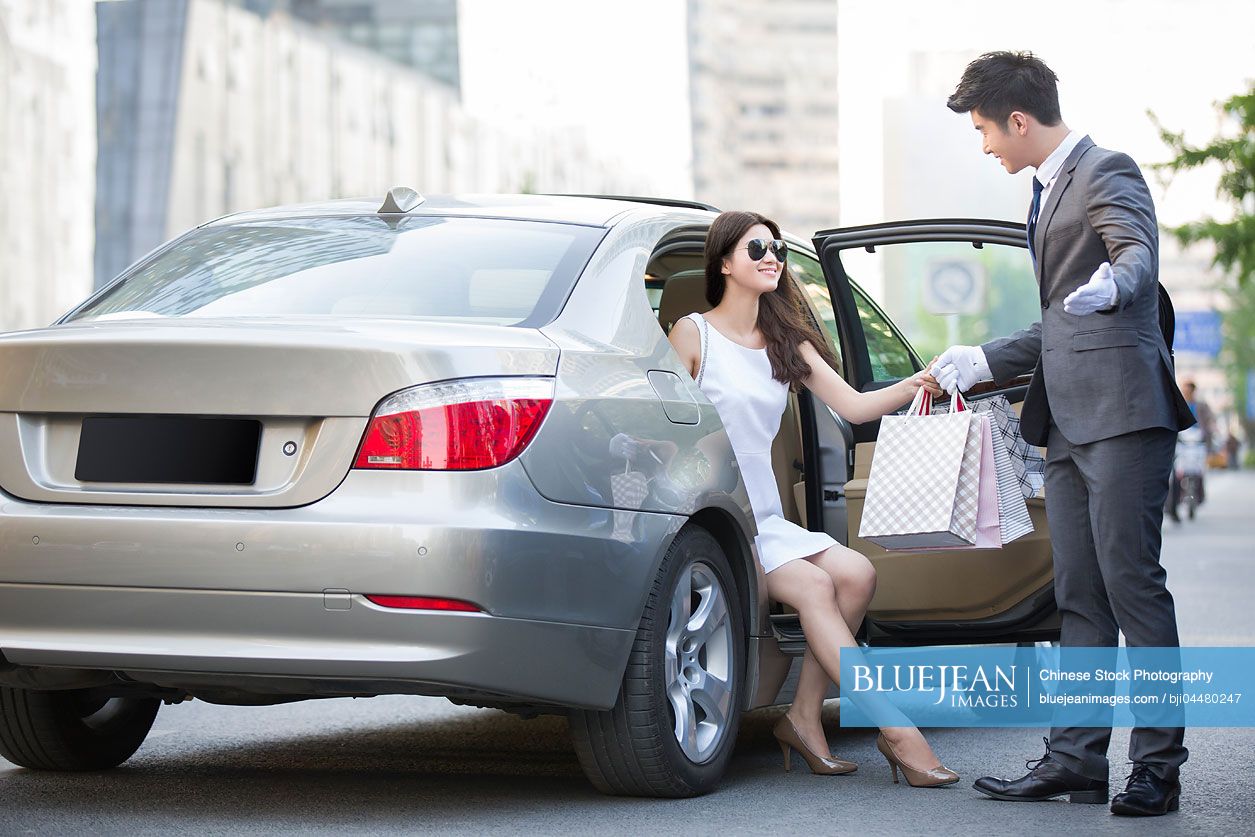 Chinese chauffeur opening car door for a young woman