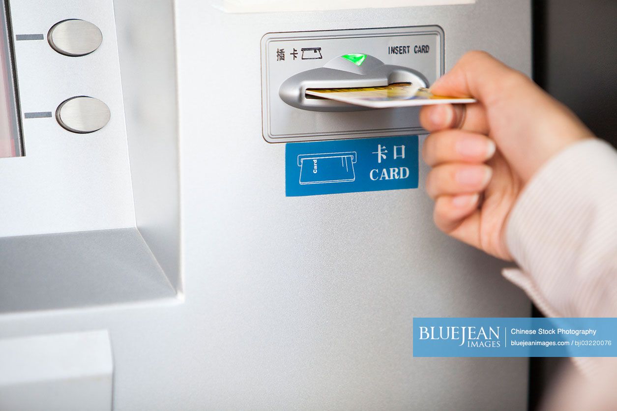 Close up of Chinese businesswoman inserting bank card into ATM