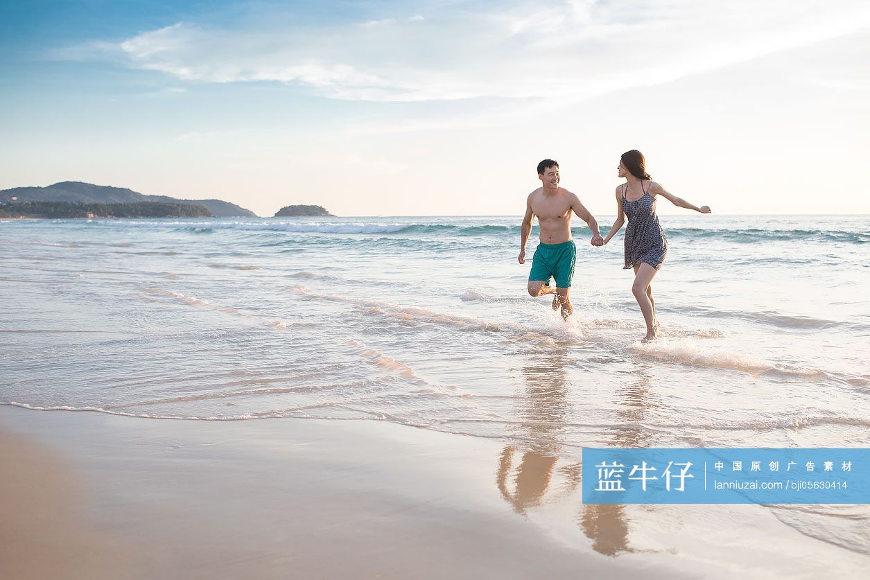 快乐的年轻情侣在沙滩奔跑