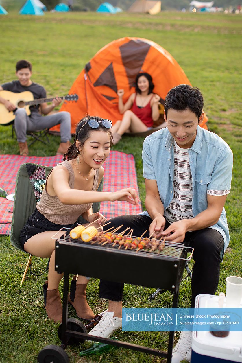 Happy young Chinese friends barbecuing outdoors