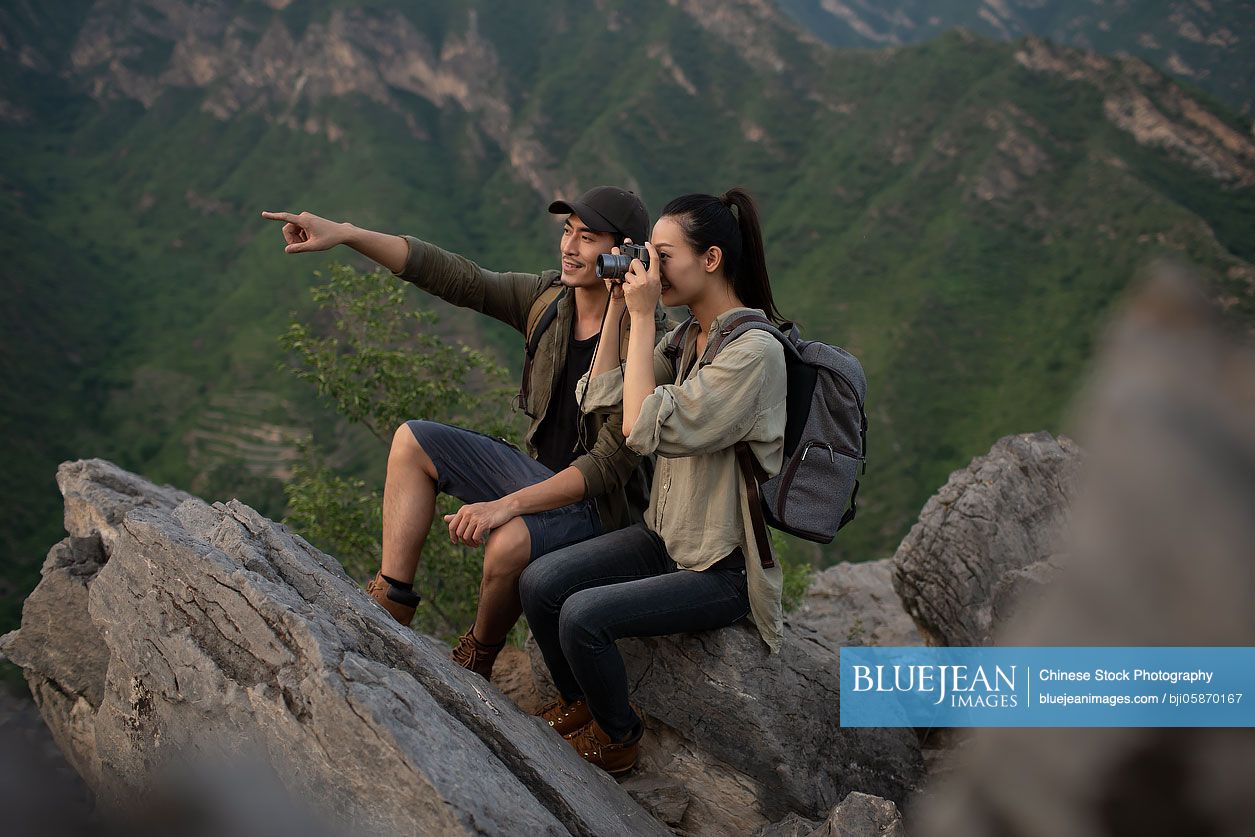 Young Chinese couple taking photos with camera outdoors